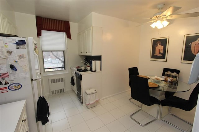 kitchen featuring radiator, white cabinets, light countertops, and freestanding refrigerator