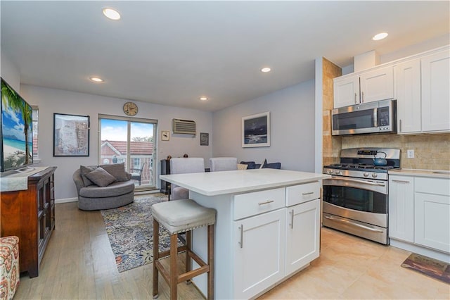 kitchen featuring a breakfast bar area, a center island, white cabinets, stainless steel appliances, and backsplash