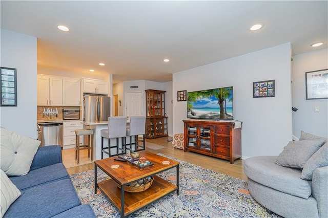 living area with a toaster, light wood-style flooring, and recessed lighting