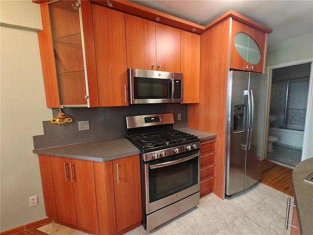 kitchen featuring appliances with stainless steel finishes, dark countertops, and brown cabinets