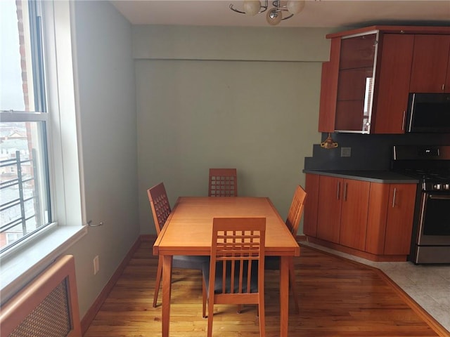 dining space featuring baseboards, light wood-style floors, and radiator