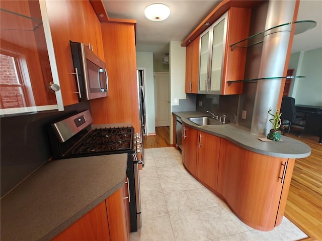 kitchen with light tile patterned flooring, a sink, appliances with stainless steel finishes, brown cabinets, and glass insert cabinets