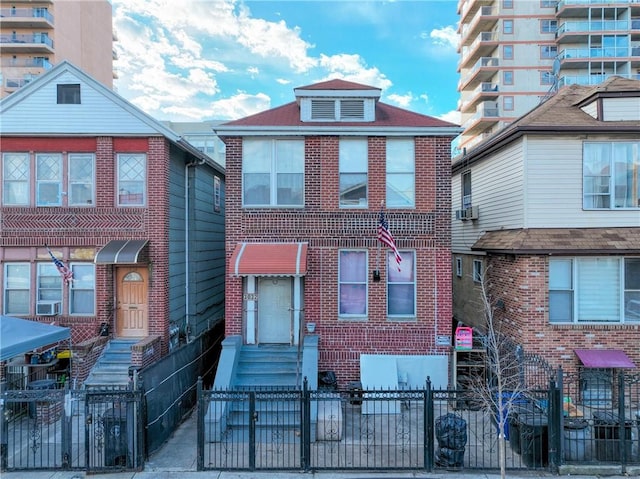 view of front facade featuring brick siding, cooling unit, entry steps, and a fenced front yard