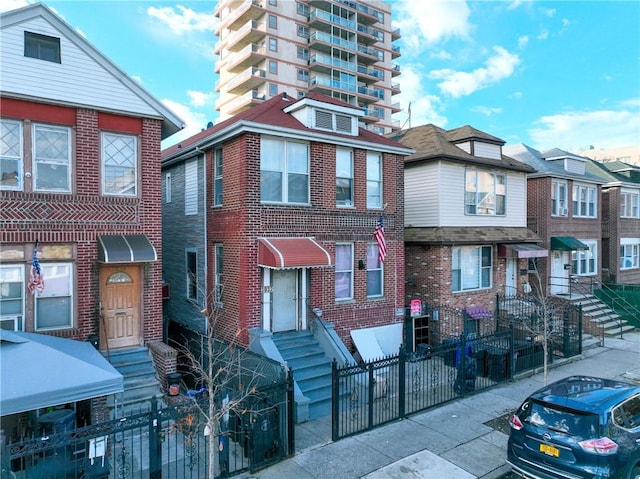 multi unit property with entry steps, a fenced front yard, and brick siding