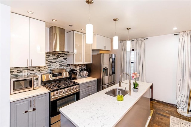 kitchen with white cabinetry, sink, gray cabinetry, stainless steel appliances, and wall chimney exhaust hood