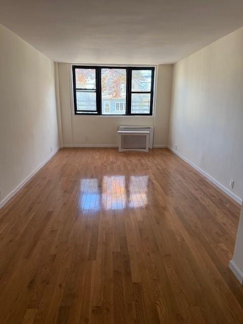 unfurnished room with baseboards and hardwood / wood-style flooring