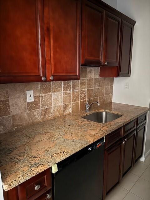 kitchen with light tile patterned flooring, black dishwasher, sink, and light stone countertops