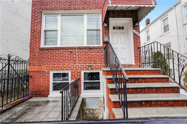 entrance to property featuring brick siding and fence