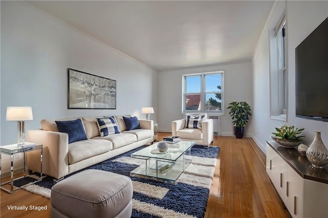 living area with radiator heating unit, baseboards, and hardwood / wood-style flooring