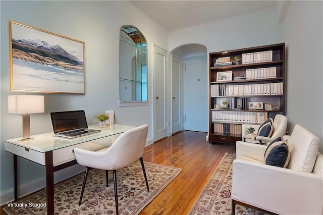 office space with arched walkways and wood finished floors