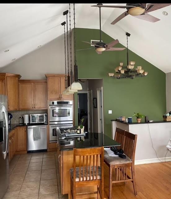 kitchen with decorative light fixtures, tile patterned flooring, decorative backsplash, a notable chandelier, and stainless steel appliances