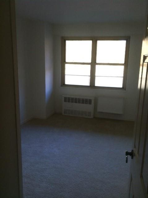 unfurnished room with carpet floors and radiator heating unit