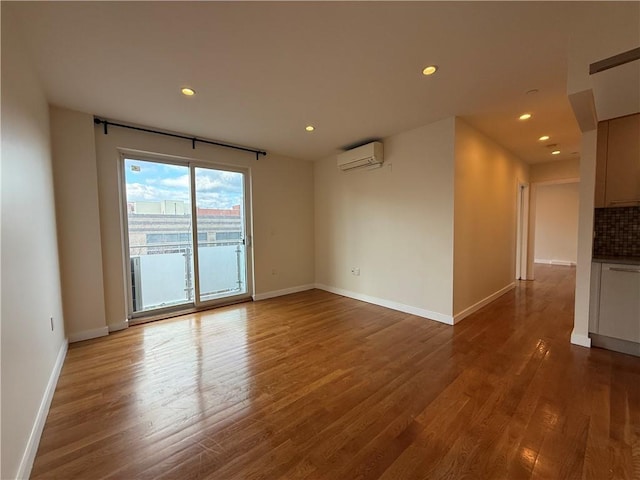 spare room featuring recessed lighting, an AC wall unit, and wood finished floors