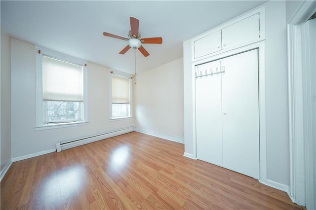 unfurnished bedroom featuring ceiling fan, a baseboard radiator, a closet, and light hardwood / wood-style floors