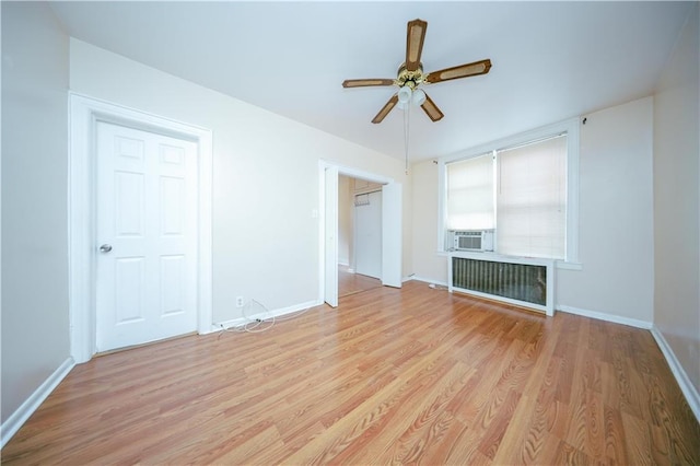 interior space with ceiling fan, cooling unit, radiator heating unit, and light hardwood / wood-style flooring