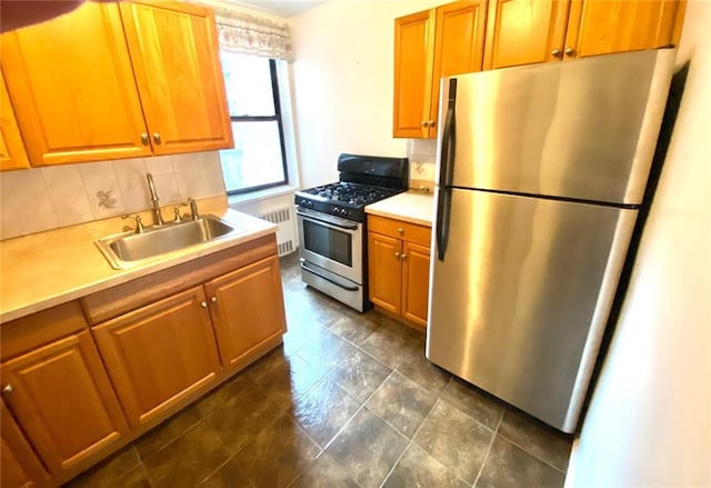 kitchen featuring stainless steel appliances, a sink, light countertops, brown cabinets, and radiator heating unit