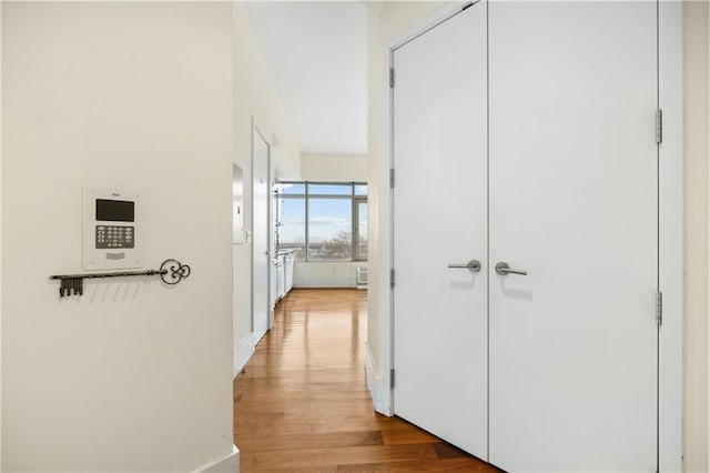 hall with baseboards and light wood-style floors