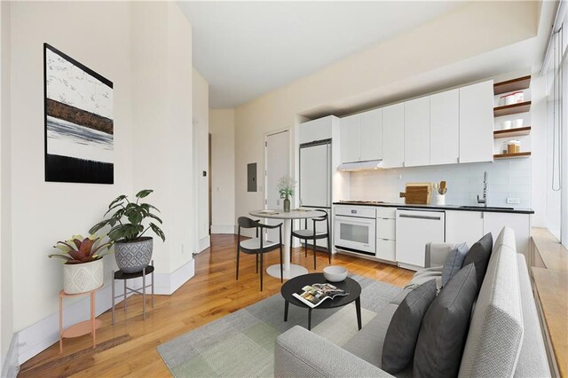 living room featuring sink, light hardwood / wood-style floors, and electric panel