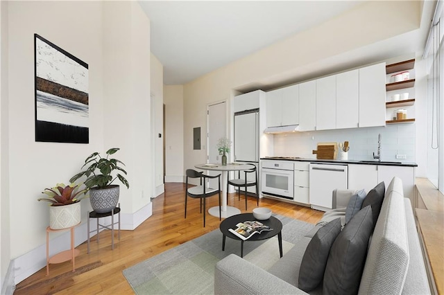 living room featuring light wood finished floors, electric panel, and baseboards