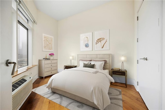 bedroom with a wall unit AC and light wood finished floors