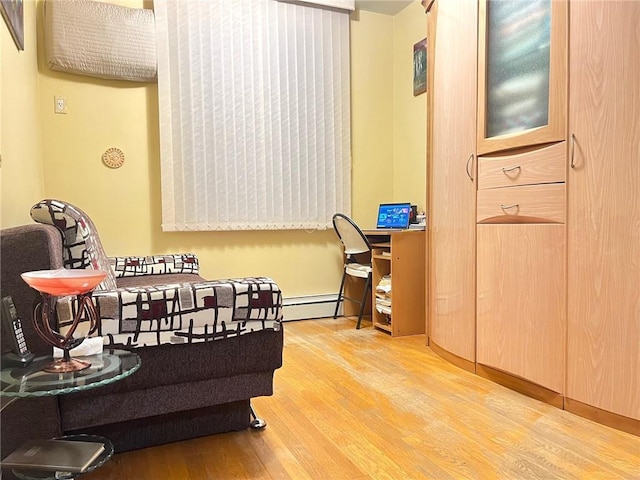 sitting room with built in desk, light hardwood / wood-style floors, and a baseboard heating unit