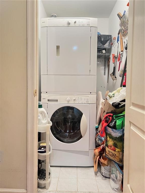 laundry room with stacked washer and dryer and light tile patterned flooring