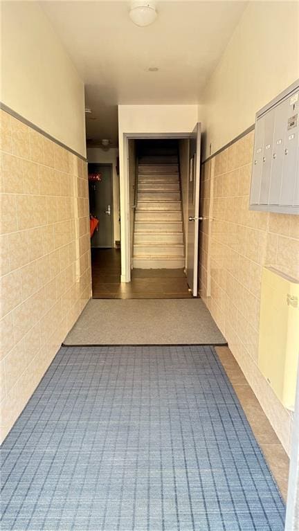 hall featuring mail boxes and tile walls