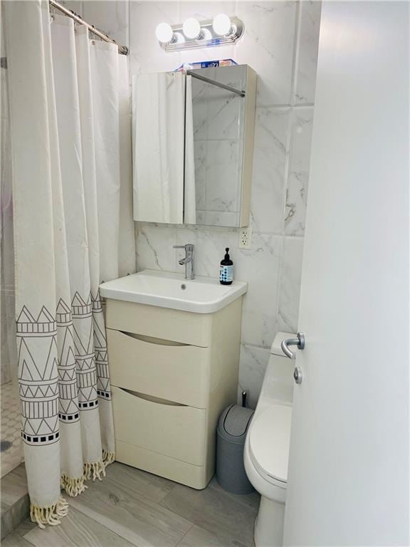 bathroom featuring curtained shower, vanity, tile walls, and toilet