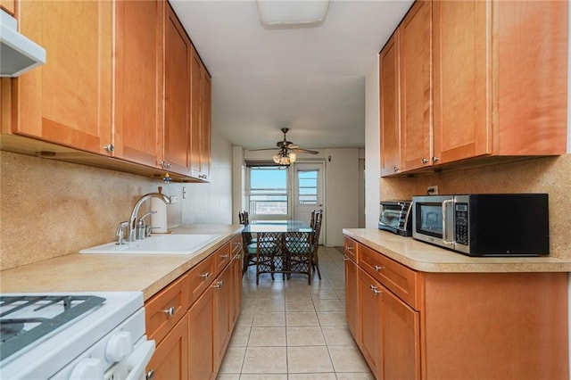 kitchen featuring stainless steel microwave, ceiling fan, under cabinet range hood, light countertops, and a sink