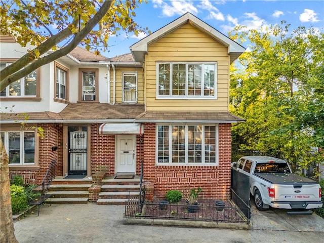 view of front of house featuring brick siding and fence