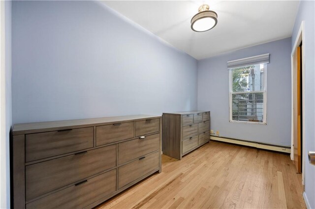 bedroom featuring light wood-type flooring and a baseboard heating unit