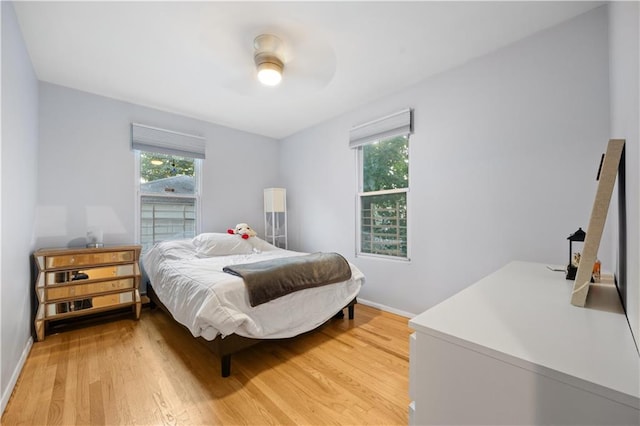 bedroom with hardwood / wood-style floors, ceiling fan, and multiple windows