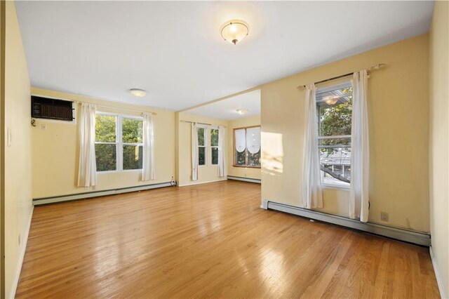 interior space with a wall unit AC, light hardwood / wood-style flooring, and a baseboard radiator