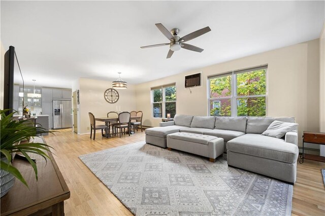 living room with ceiling fan, light hardwood / wood-style floors, a wealth of natural light, and a wall mounted AC