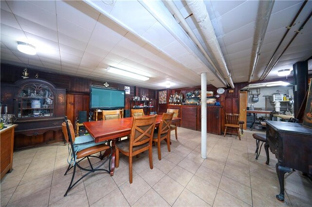 tiled dining room featuring indoor bar and wooden walls