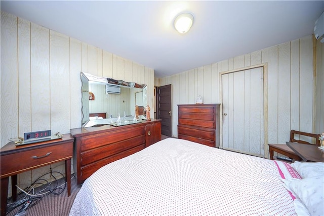 bedroom with wooden walls, a wall mounted AC, a closet, and dark colored carpet