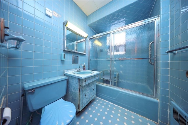 full bathroom with toilet, vanity, shower / bath combination with glass door, and tile walls