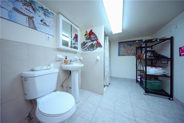 bathroom with toilet, curtained shower, sink, and tile walls