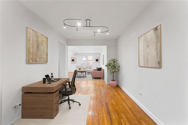 office space with light wood-type flooring and rail lighting