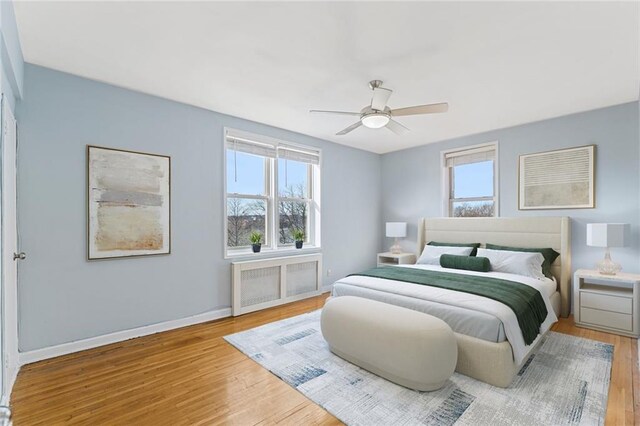 bedroom with wood-type flooring, radiator heating unit, and ceiling fan