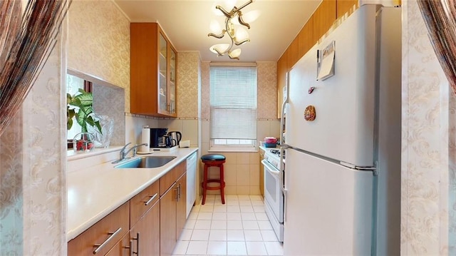 kitchen featuring light tile patterned flooring, white appliances, and sink