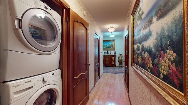 clothes washing area featuring light hardwood / wood-style floors, stacked washing maching and dryer, and ornamental molding