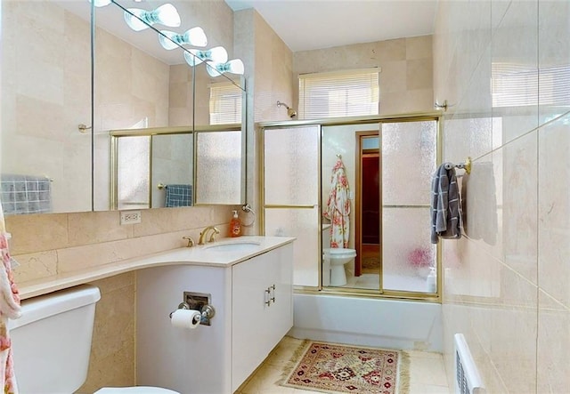 full bathroom featuring tile patterned floors, toilet, combined bath / shower with glass door, and tile walls