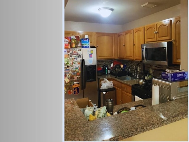 kitchen with tasteful backsplash, sink, stone countertops, and appliances with stainless steel finishes