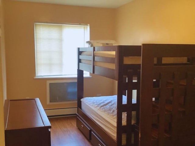 bedroom with hardwood / wood-style floors and a baseboard radiator