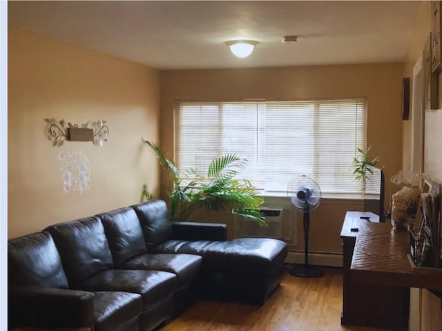 living room with wood-type flooring, baseboard heating, and a wall unit AC