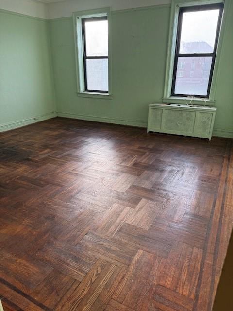 spare room featuring radiator and dark parquet flooring