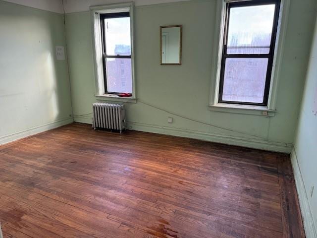 empty room featuring radiator heating unit and dark hardwood / wood-style flooring