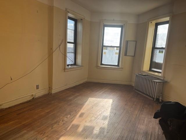 unfurnished room featuring radiator heating unit and wood-type flooring