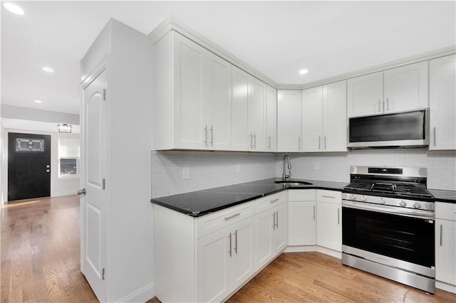 kitchen featuring white cabinetry, sink, light hardwood / wood-style floors, and appliances with stainless steel finishes